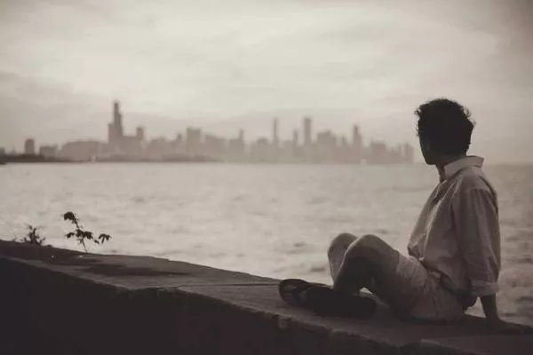 A boy gazing across water towards a city